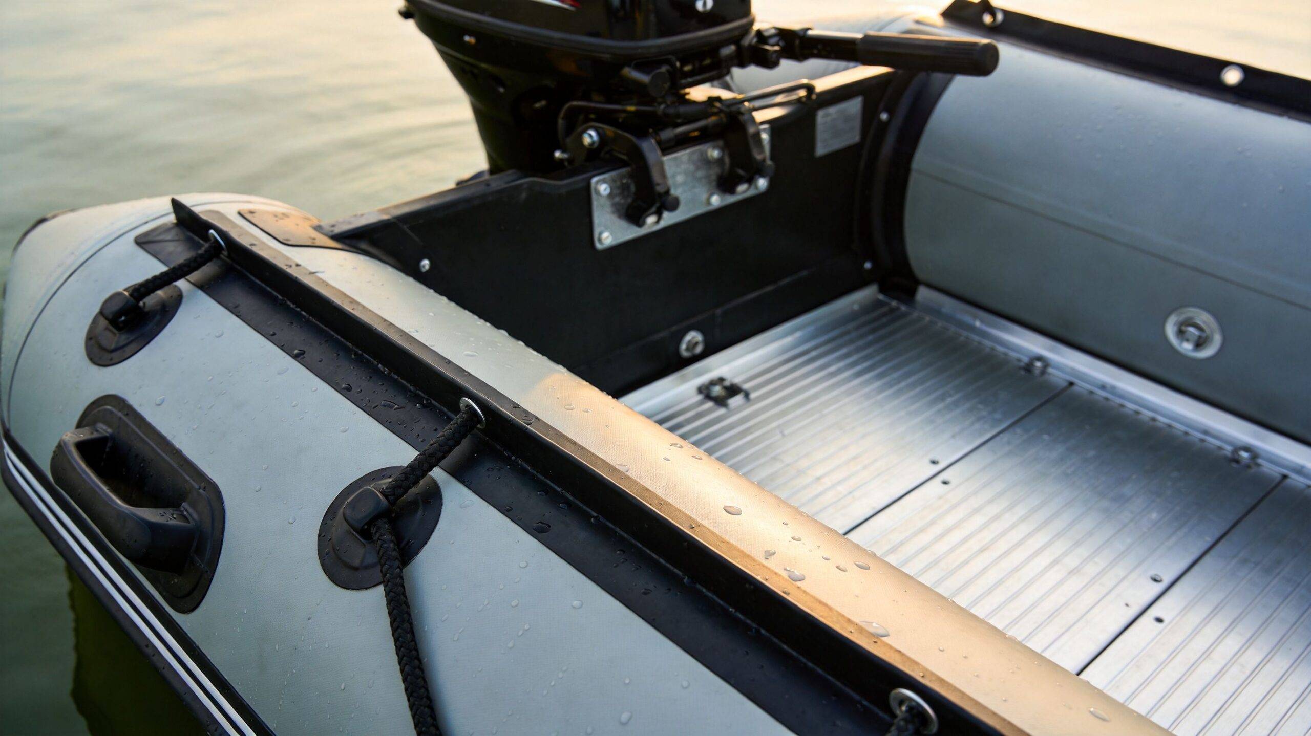 A close-up view of the interior deck and stern of an inflatable motorised boat on water.